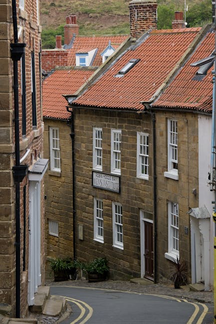 Historic brick houses with red roofs on a narrow street in Robin Hood's Bay, England.