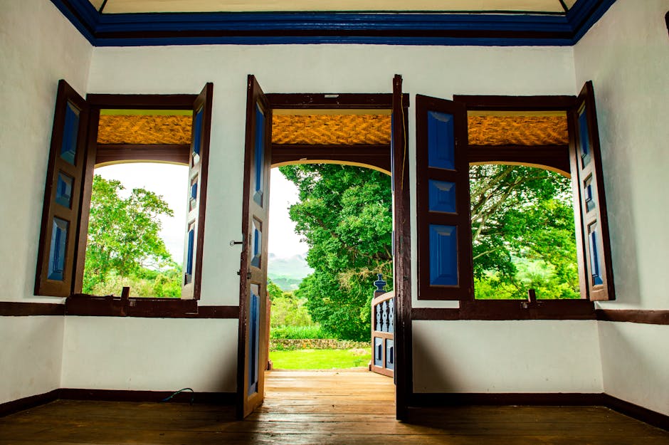 Inviting interior with classic wooden doors and vibrant outdoor greenery, showcasing colonial architecture.