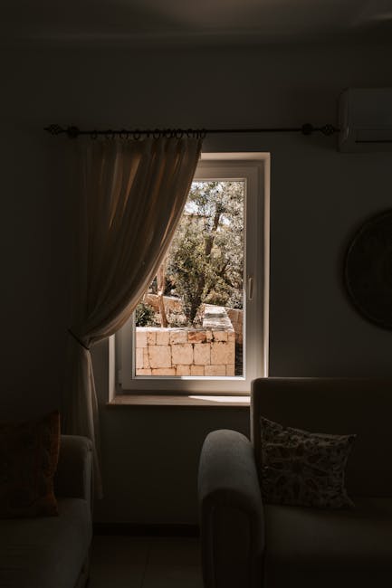 Warm and inviting living room interior with a sunlit window view, featuring modern furniture.
